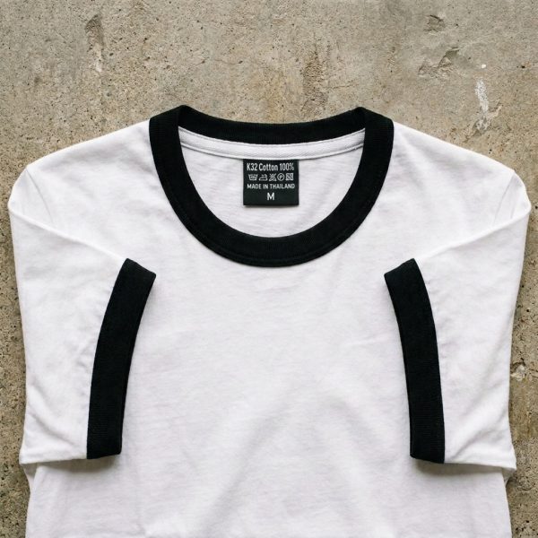 ภาพถ่าย Flat Lay เสื้อยืดสไตล์เรโทร Ringer Tee สีขาวขอบสีดำบนพื้นปูนดิบ